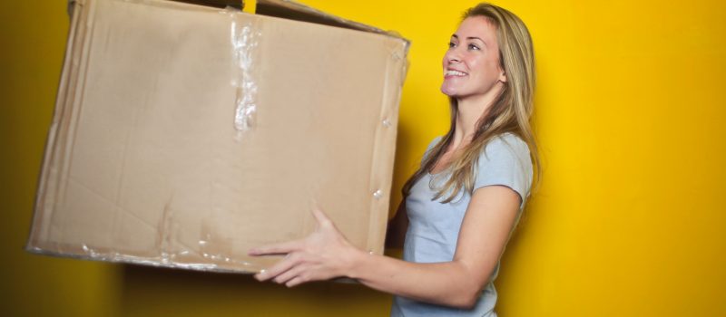Female holding a large cardboard moving box